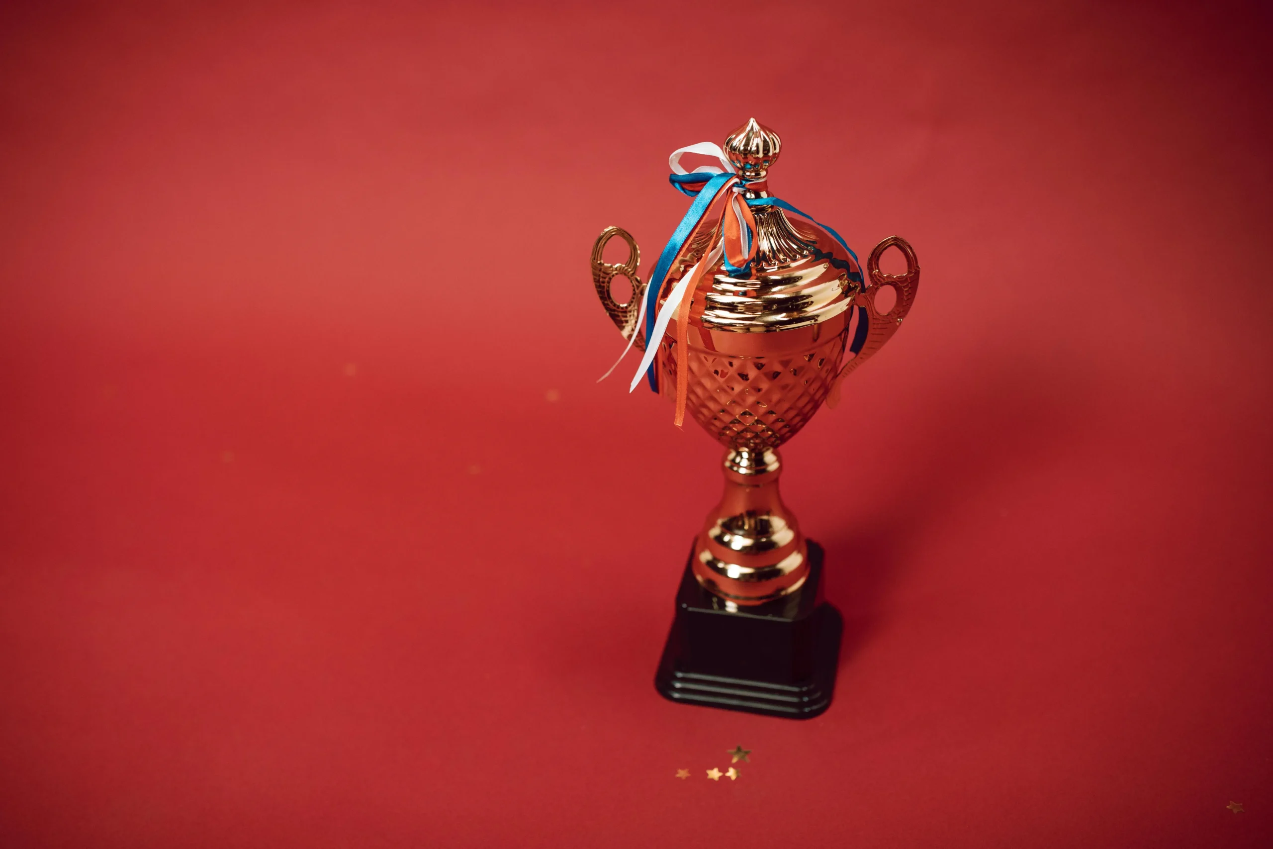 A Trophy with Tied Ribbons on Red Background (https://www.pexels.com/photo/a-trophy-with-tied-ribbons-on-red-background-7005687/)